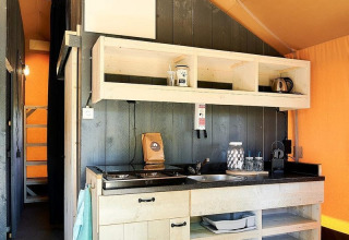Keukengedeelte bij een safaritent in Glamfield Lodge I, Wilsumer Berge, Duitsland, met houten rekken.