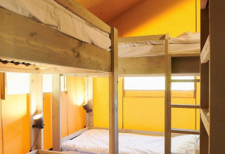 Interieur van Glamfield Lodge I safaritent met stapelbedden en gele muren in Wilsumer Berge, Duitsland.