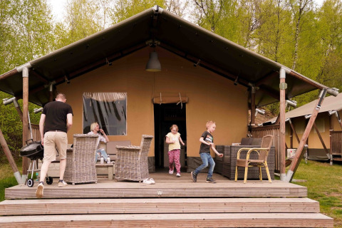 Gezin op het terras van safaritent Glamfield Lodge I in Wilsumer Berge, Duitsland, geniet samen.