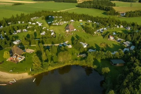 Aerial view of Campsite Hunze Bulten in Drenthe, Netherlands, featuring green fields and a lake.
