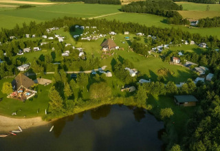 Vista aerea del campeggio Hunze Bulten a Drenthe, Paesi Bassi, circondato da campi verdi e un lago.