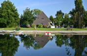 A-frame cabin reflected in calm lake at Campsite Hunze Bulten, a holiday park in Drenthe, Netherlands.