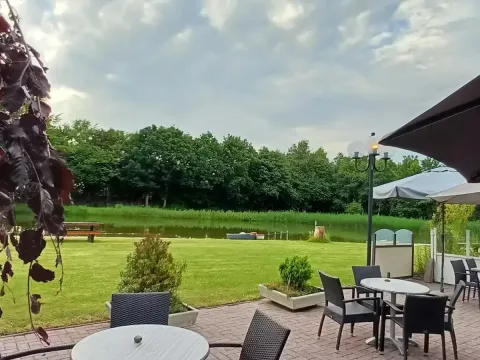 Terrazza all'aperto con tavoli vicino allo stagno al campeggio Hunze Bulten a Drenthe, Paesi Bassi.