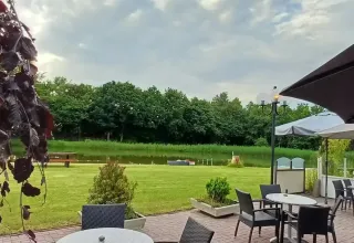 Terrazza all'aperto con tavoli vicino allo stagno al campeggio Hunze Bulten a Drenthe, Paesi Bassi.