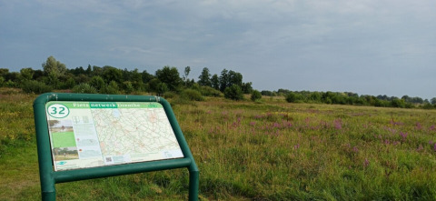 Cartello informativo Fiets Netwerk Drenthe vicino a un campo verde al campeggio Hunze Bulten, Drenthe, Paesi Bassi.