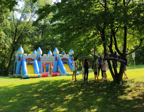 Bambini vicino a un castello gonfiabile e al cartello 'Plaine de jeux' in un parco in Francia.