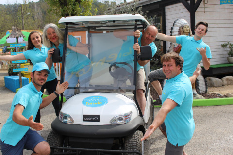 Grupo de personas con polos azules posando y sonriendo junto a un carrito en Camping Paradis Family des Issoux, Francia.