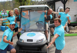 Grupo de personas con polos azules posando y sonriendo junto a un carrito en Camping Paradis Family des Issoux, Francia.