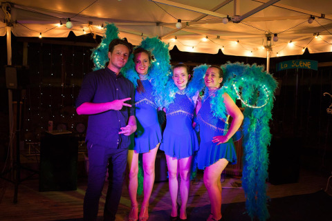 Man en drie vrouwen in blauwe verenoutfits poseren samen op het podium bij Camping Paradis Family des Issoux.