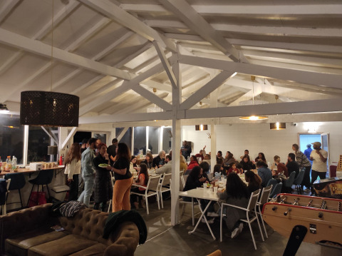 Gruppe af mennesker samles til middag i en hyggelig, lyst oplyst hytte ved Family's Camping Le Savoy.