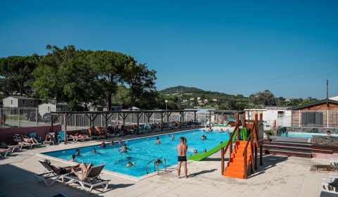 Piscina all'aperto con bambini, adulti, lettini e scivolo al Flower Camping Provence Vallée, Francia.