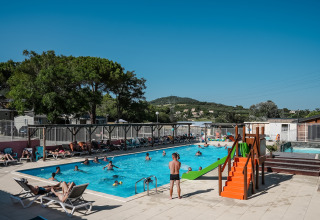 Piscina all'aperto con bambini, adulti, lettini e scivolo al Flower Camping Provence Vallée, Francia.