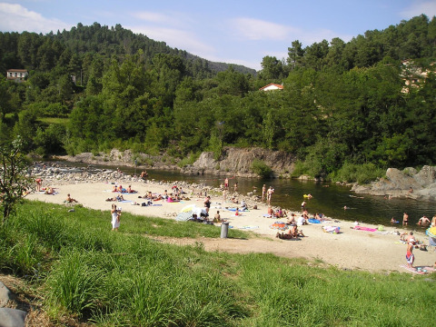 Menschen entspannen am Flussstrand mit Handtüchern und Badekleidung am Camping Paradis Family des Issoux.
