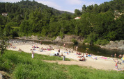 Mensen op een rivierstrand genieten van de zon bij Camping Paradis Family des Issoux in een groene vallei.