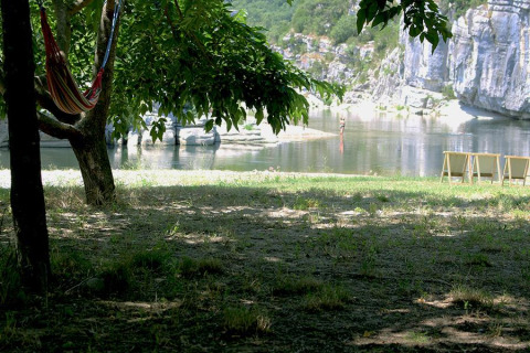 Skyggefuldt område med hængekøje under træer ved flod, klipper og liggestole, Camping Paradis Family des Issoux.