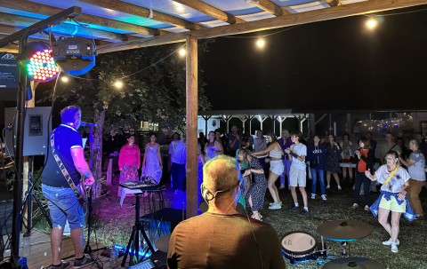 Concerto di una band dal vivo di sera al Family's Camping Le Savoy con ospiti che ballano all'aperto.