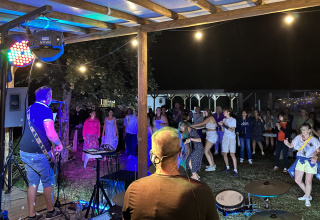 Banda en vivo tocando de noche en Family's Camping Le Savoy, con huéspedes bailando y disfrutando.