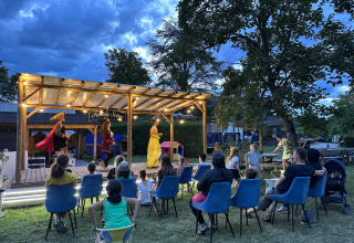 Spectacle familial en plein air le soir au Family's Camping Le Savoy, avec public assis devant la scène.