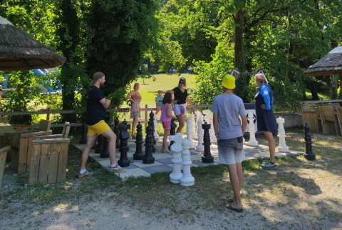 Familien genießen ein Schachspiel auf einem übergroßen Outdoor-Schachbrett in einem Ferienpark.