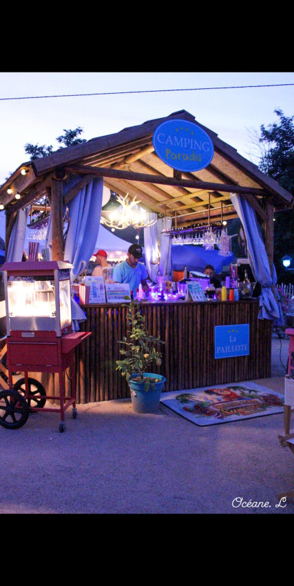 Stand en bois éclairé au Camping Paradis Family des Issoux en Auvergne-Rhône-Alpes, France, de nuit.