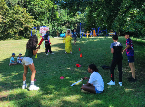Bambini giocano con adulti in costume su un parco giochi al Family's Camping Le Savoy, Auvergne-Rhône-Alpes, Francia.