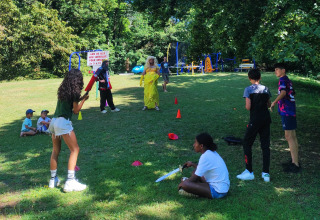 Bambini giocano con adulti in costume su un parco giochi al Family's Camping Le Savoy, Auvergne-Rhône-Alpes, Francia.