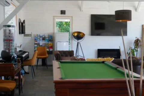 Sala de recreo en Family's Camping Le Savoy con mesa de billar, sofás, televisor, piano y folletos.
