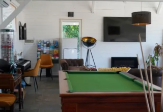 Fællesrum på Family's Camping Le Savoy med billardbord, tv, sofaer, klaver og informationsbrochurer.
