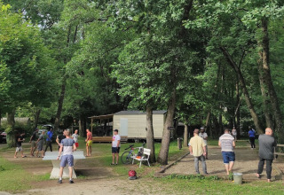 Feriepark med mennesker, der spiller bordtennis og petanque blandt træer i Camping Le Savoy, Frankrig.