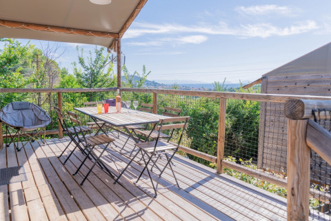 Terrazza in legno con tavolo e sedie, vista panoramica su Flower Camping Provence Vallée in Francia.