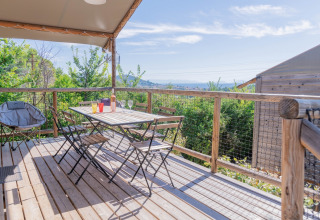 Wooden terrace with seating area and scenic view at Flower Camping Provence Vallée in southern France.