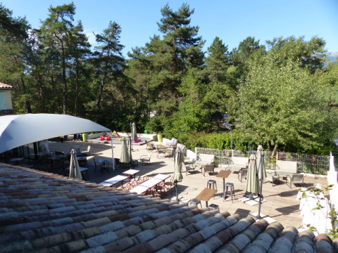 Outdoor terrace at Flower Camping la Pinède holiday park in Auvergne-Rhône-Alpes, France, surrounded by trees.
