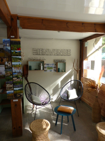 Bright, welcoming lounge area at Flower Camping la Pinède, France, with modern chairs and postcards display.
