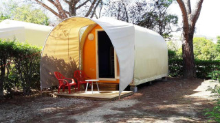 Coco Sweet safari tent without sanitary facilities, two red chairs in front, surrounded by trees.