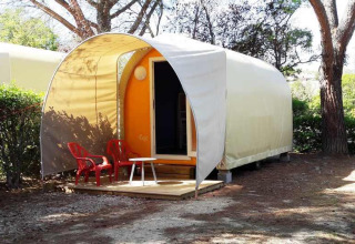 Coco Sweet safari tent without sanitary facilities, two red chairs in front, surrounded by trees.