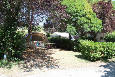 Teltplads i skyggefuldt område med træer og buske på Flower Camping Provence Vallée i Provence, Frankrig.