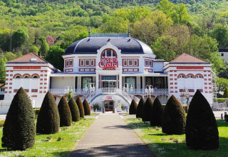 Façade du casino New Castel près de Challes les Eaux, Auvergne-Rhône-Alpes, entourée de collines verdoyantes.