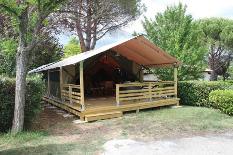 Wooden tent with veranda in a green setting at Flower Camping Provence Vallée, Provence-Alpes-Côte d’Azur.