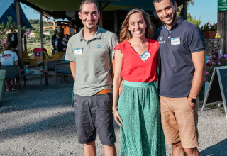 Drei lächelnde Erwachsene posieren draußen bei Flower Camping Provence Vallée in Südfrankreich.