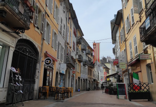 Gezellig, smal straatje met kleurrijke gevels en terrasjes in een Frans dorp, Auvergne-Rhône-Alpes.