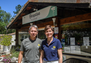 Dos personas están de pie frente a la recepción de Flower Camping la Pinède en Auvergne-Rhône-Alpes, Francia.
