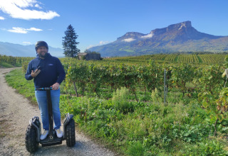 Mand på en Segway kører langs en vinmark med bjerge i baggrunden i Auvergne-Rhône-Alpes, Frankrig.