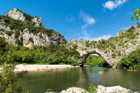 Des kayakistes pagayant sur la rivière sous l'arche naturelle du Pont d’Arc près de Lalevade d'Ardèche.