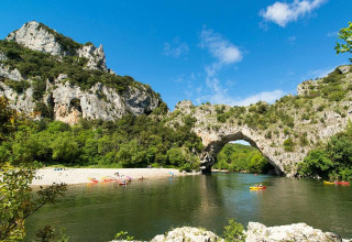 Des kayakistes pagayant sur la rivière sous l'arche naturelle du Pont d’Arc près de Lalevade d'Ardèche.