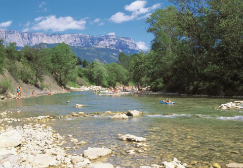 Le parc de vacances Flower Camping la Pinède en Auvergne-Rhône-Alpes avec des gens se baignant dans une rivière.