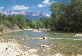 Le parc de vacances Flower Camping la Pinède en Auvergne-Rhône-Alpes avec des gens se baignant dans une rivière.