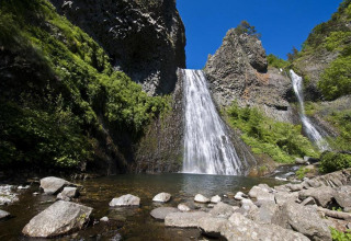 Suggestiva cascata tra le rocce e il verde vicino a Lalevade d'Ardèche, in Auvergne-Rhône-Alpes, Francia.