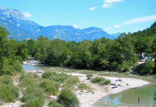 Fiume con bagnanti, alberi verdi e montagne presso Flower Camping la Pinède in Auvergne-Rhône-Alpes.