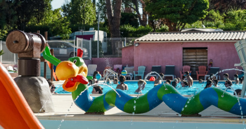 Des enfants jouent dans une piscine avec des sculptures arroseuses colorées au Flower Camping Provence Vallée, France.
