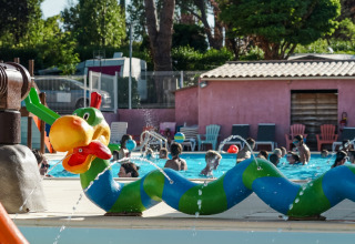Kinder spielen in einem Pool mit bunten Wasserskulpturen im Flower Camping Provence Vallée in Frankreich.